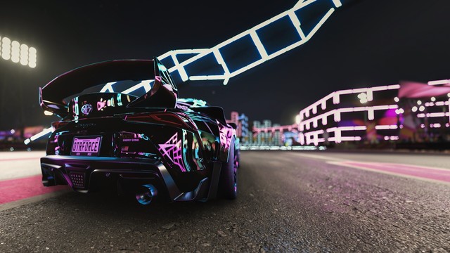 Wide angle shot from behind of a black and gold 2020 Toyota GR Supra reflecting magenta, cyan, and yellow neon slights with a blurred background.