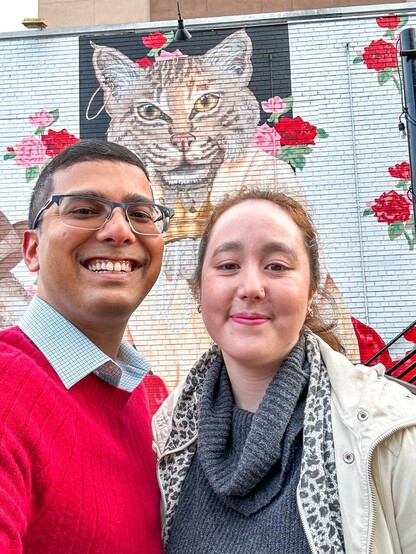 A couple standing in front of a cat mural