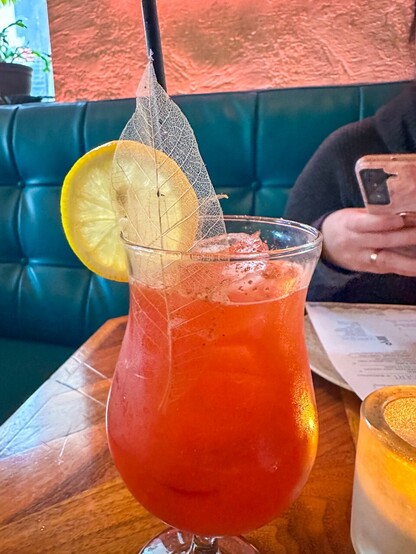 A cocktail garnished with lemon and a leaf skeleton
