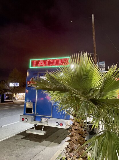 A food truck displaying “TACOS” on an illuminated sign