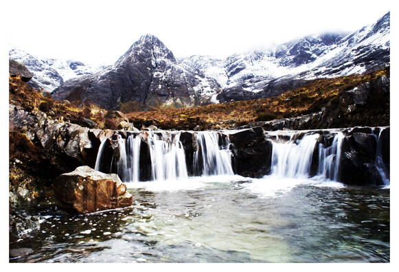 Background of snowy mountains with the foreground of waterfalls. The fairy pools on Skye, Scotland.