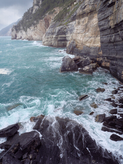 A seascape view with waves crashing on the rocks and the coastline going into the distance.