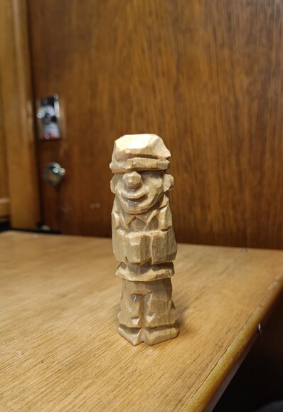 Wood carving of a man with a cap.