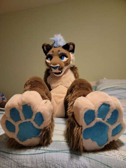 Lioness fursuiter sitting on bed showing toe beans