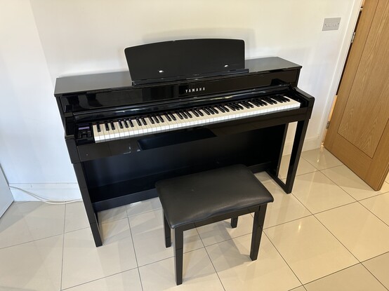 A black Yamaha CLP-575 piano and bench