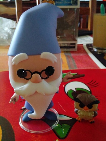 Une figurine POP représentant le personnage du film éponyne des studios Disney Merlin l'Enchanteur et son hibou Archimède
