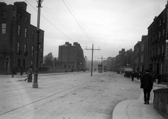 A black and white photograph taken c1911 of very wide and a very empty Baggot Street close to Dublin's city centre, but there are some trams and pedestrians.