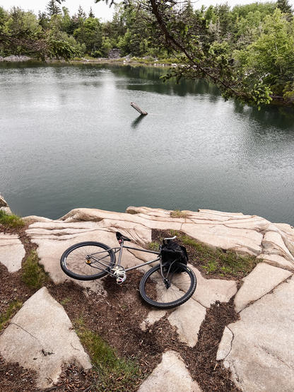 A bicycle with big front rack packed with goodies, layong in an abandoned quarry.