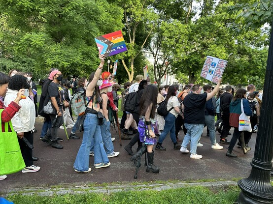 A group of marchers carrying signs. One reads "Queer Asylees are welcome here".