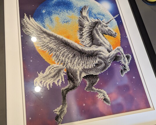 A diamond dotz picture of a pegacorn in the night sky in front of moon