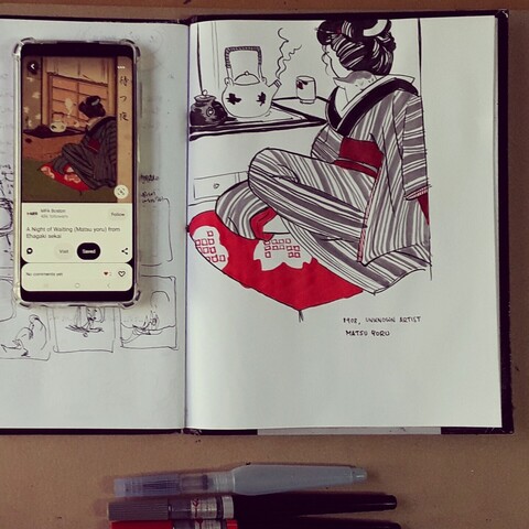 A photograph taken from above; a sketchbook, a smartphone and three brushes on the drawing table: the smartphone shows the image used as a reference - a japanese interior with a woman dressed in kimono preparing tea; a cat head can be seen under the robe. On the sketchbook some brush strokes exercises using the image as reference. An empty waterbrush for black ink and two brushpens, red and gray, sit on the bottom of the picture.