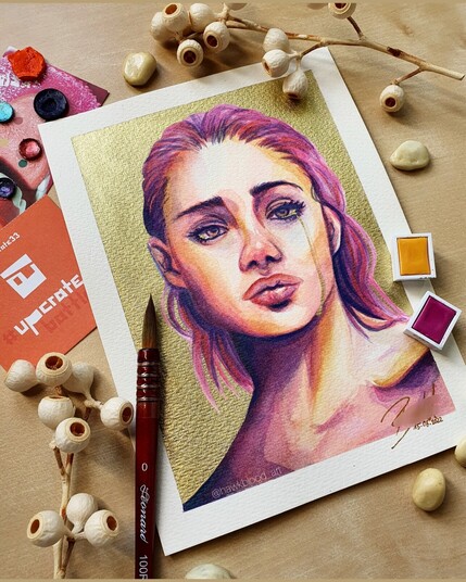 A watercolor painting of a woman with a concerned expression. The background is golden and a small golden tear runs over her face.
The artwork is photographed surrounded by the supplies used and dried berries