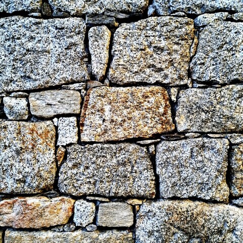 Detail of a dry stone wall in which smaller stones perfectly fill the gaps between the large stones of irregular shape.