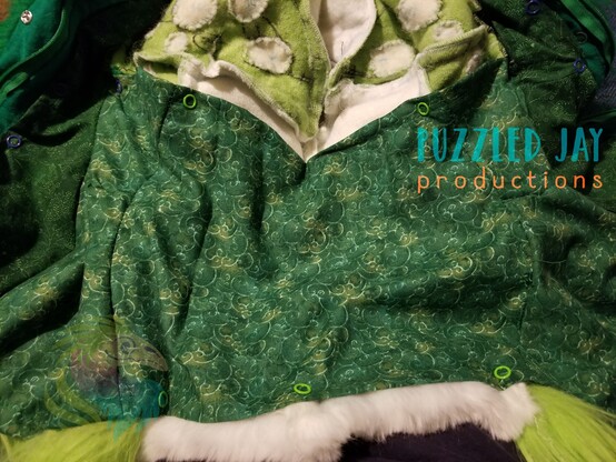 A green & white cowl made of faux fur, with an added white lower jaw. Macro image of white spots in bright green fur. Interior image of cowl with removable cotton lining (fastened by snaps to the backside of the faux fur).