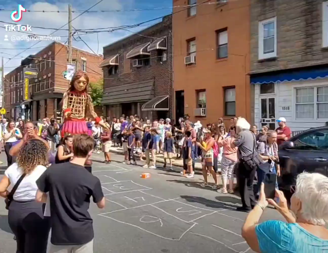 A 12 foot puppet named Little Amal attempts to play hopscotch on a street in Philadelphia Pennsylvania while raising money and awareness for immigrants and refugees around the globe.

Little Amal is a global symbol of the plight of refugees and their human rights since she was first created two years ago.