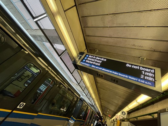 a photo of a metro station platform with an electronic board showing the message do not board while a metro train is stopped
