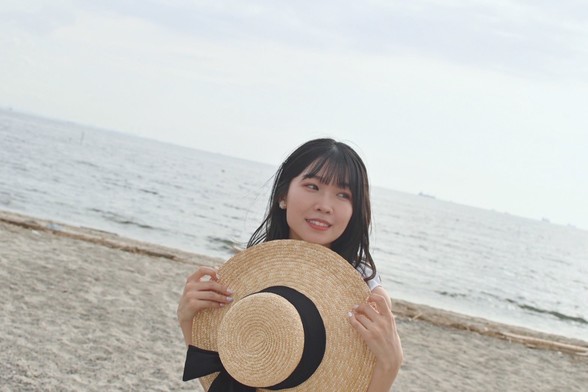 Shu Uchida holding a hat on the beach.