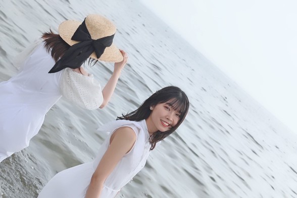 Shu Uchida and Akari Kito on the beach in white dresses.