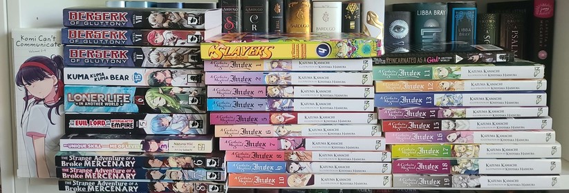 Image shows manga and Light novels stacked on a shelf. 

They include a boxset of Komi Can't Communicate Volumes 1-4, This Is Screwed up, but I Was Reincarnated as a GIRL in Another World! Volume 8, Berserk of Gluttony Volumes 2, 6, and 7, The Strange Adventure of a Broke Mercenary volumes 6-8, A Certain magical Index volumes 1-19, Slayers hardcover volume 4, Kuma Kuma Kuma Bear volume 15, Loner Life In Another World volume 6, My Unique Skill Makes Me OP even at Level 1 volume 3, and I'm the Evil Lord of an Intergalactic Empire! volume 5