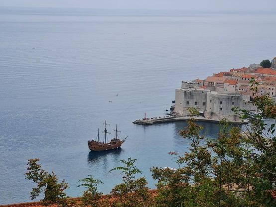 You're looking from a high spying vantage point through the leaves of some trees at a vast blue sea with a pirate ship in it that you just know is playing some kind of jolly song for tourists that are having to pay exorbitant fees for getting sunburned for their selfies. And they like it. The ship is approaching the city walls of the old city of Dubrovnik which are greyish limestone, old looking and just looking at them you know they contain the kind of tourist tat that will bankrupt you for years to come and make you question why you brought it the minute you get home. BUT importantly, you will like your holiday. Because the sun is out and things are very very beautiful.
