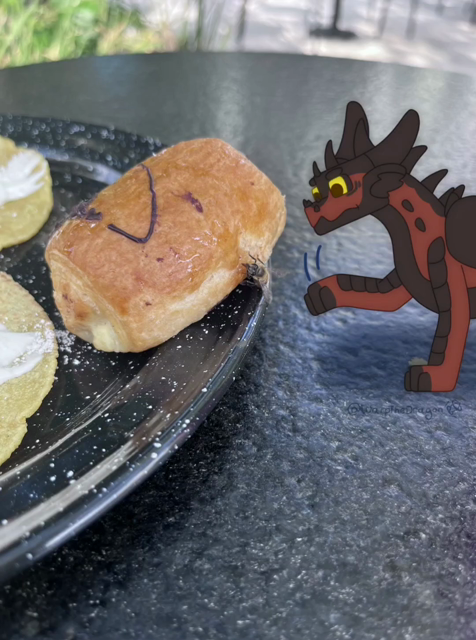 A 2 frame gif of Koza, a red and black dragon, swiping at a fly on a bun.