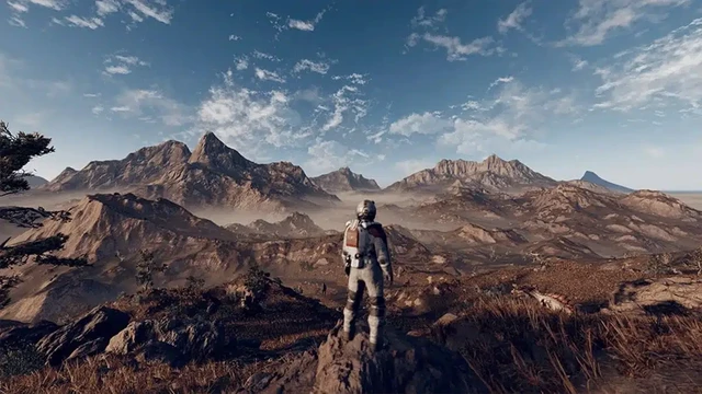 Screenshot of the game Starfield, showing a human in a space suit standing in the centre of a mountainous landscape over looking the area.