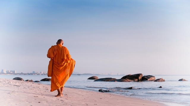 Buddhist monastics walking on a beach.