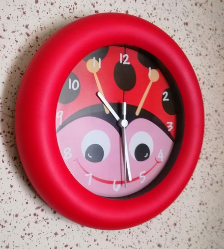 A cute wall clock depicting a smiling ladybug on its face.