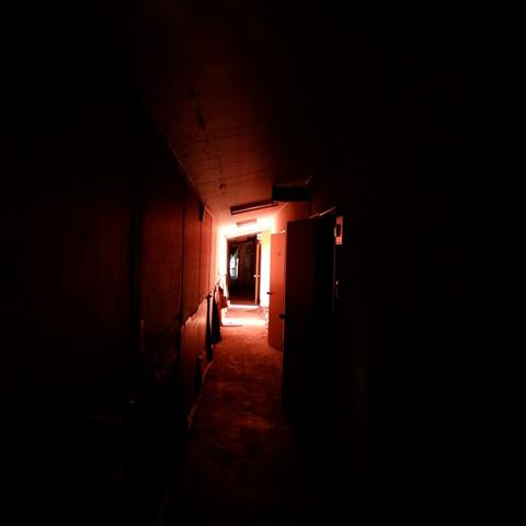 A dark corridor with light spilling through the door at the end. The paint seems to be red.