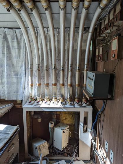 A number of vaccume tubes disappearing into a box of mangled electronics in an abandoned hotel.