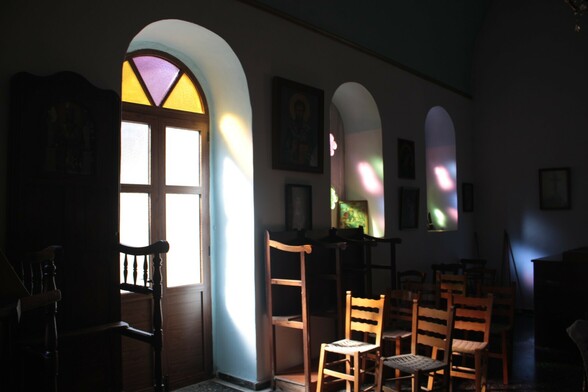 Interior of Greek Ordodox church - quite dark, showing the light filtered through the coloured glass