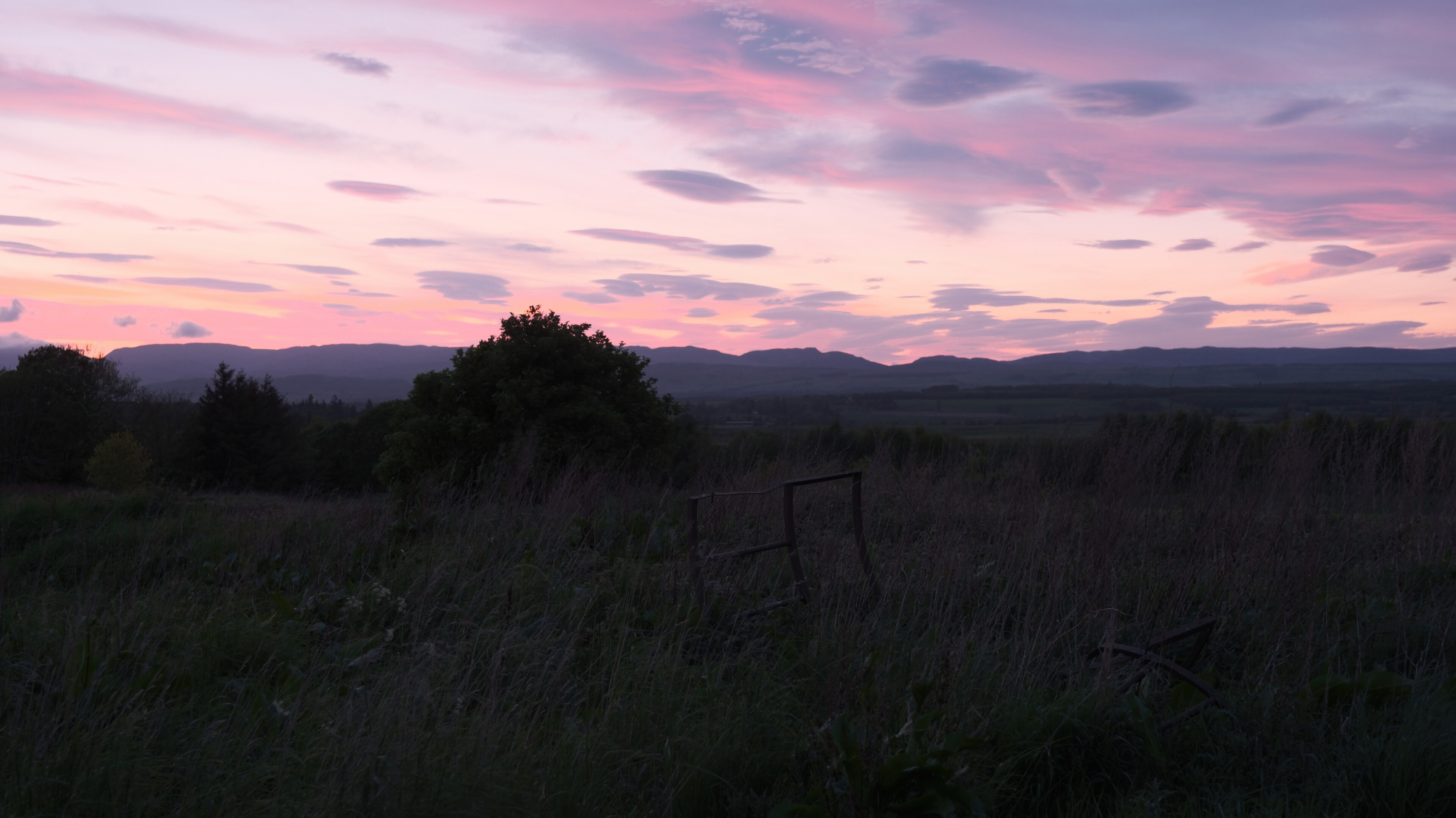 Remains of a colourful sunset contrasting with the dull green of scrap metal abandoned in the foreground