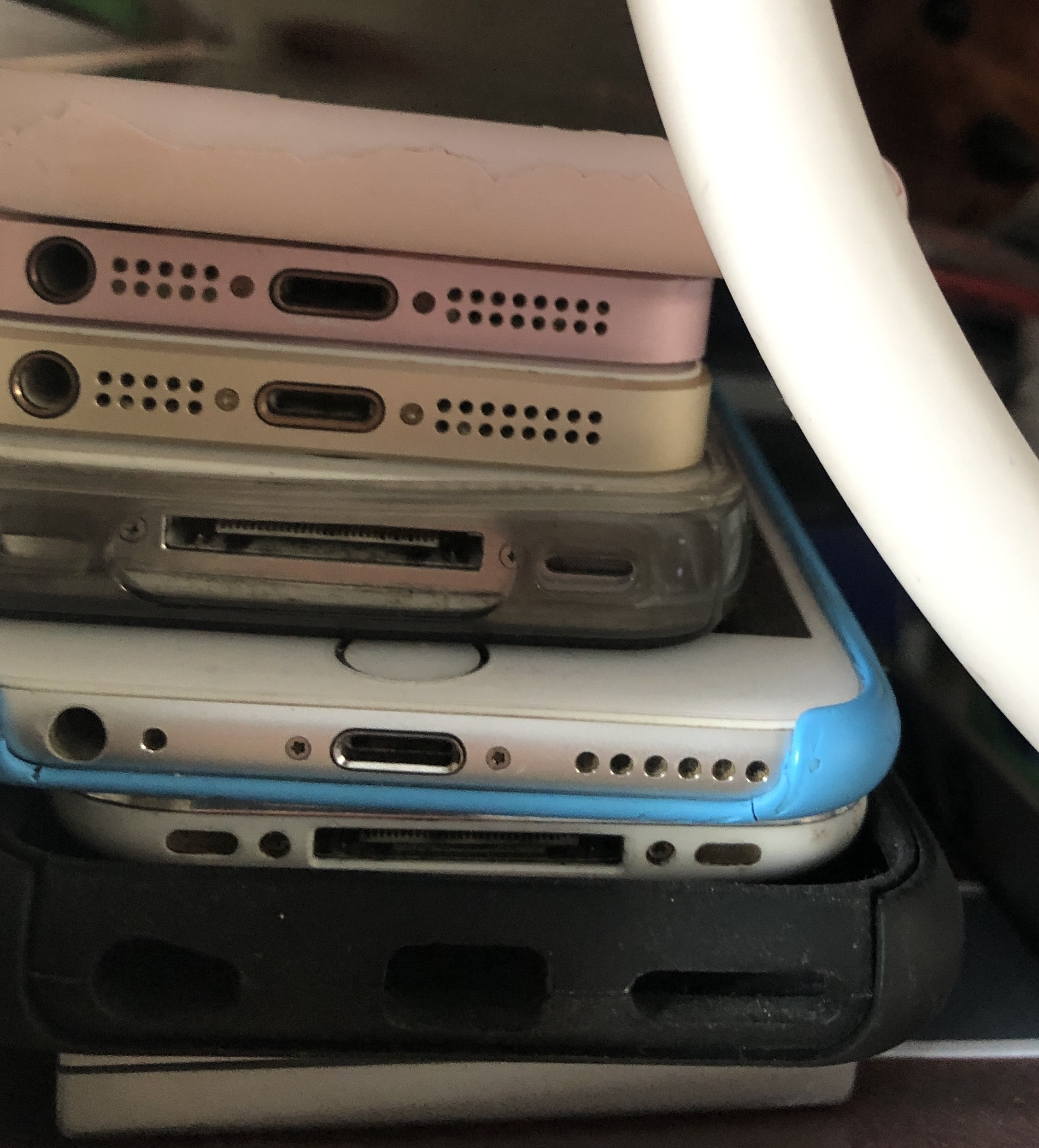 A pile of old, out of date iPhones - viewed from the bottom of the devices showing Lightning and iPod type connections.