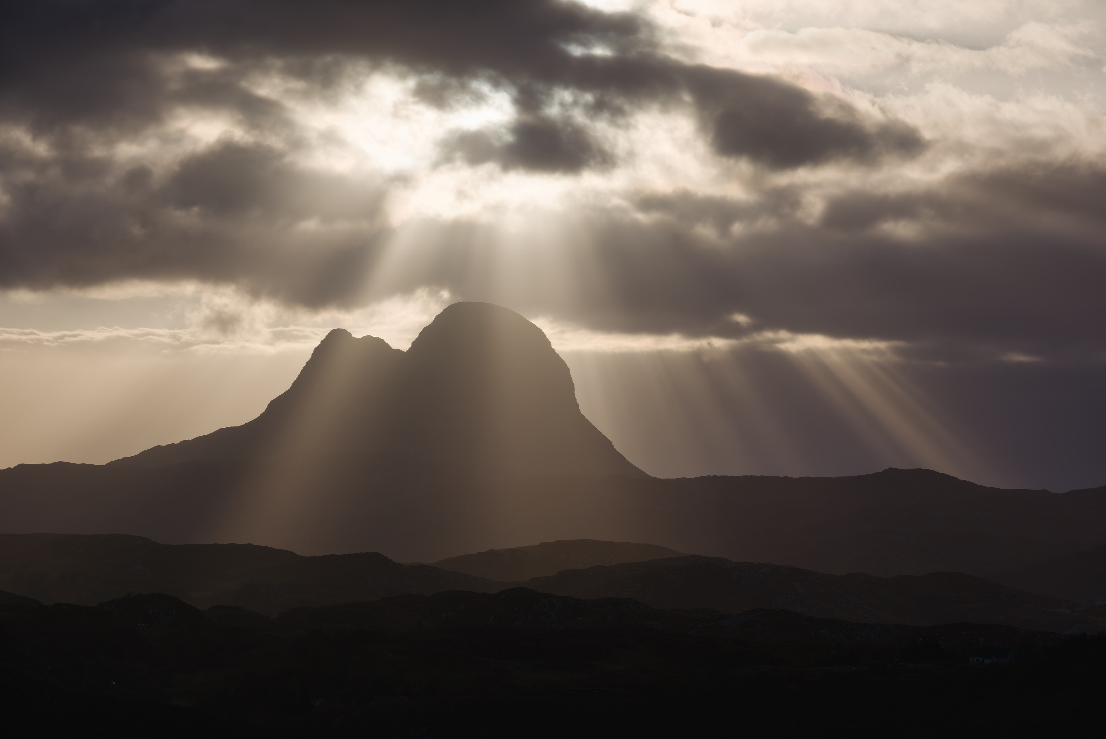 Beautiful warm sunlight and crepuscular rays behind Suilven