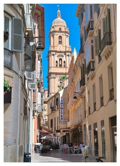 Colour portrait photograph showing a Spanish street with a restaurant at the bottom.