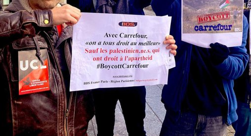 Action BDS à Montreuil contre Carrefour, novembre 2023 : 3 camarades de l'UCL avec à gauche un autocollant UCL et des affiches A3 couleur BDS