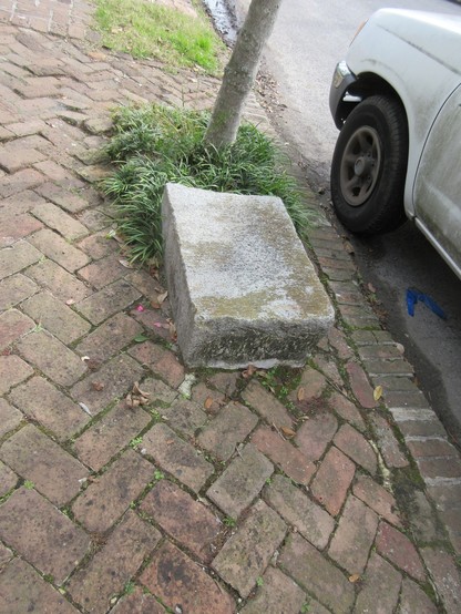 19th century carriage stone - rectangular stone block, about meter long, half meter wide and high, embedded near curb of brick sidewalk.