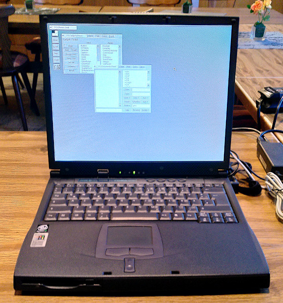 Foto: Ein altes Acer Notebook mit dem grafischen Modus von Oberon auf dem Display. Das Notebook steht auf einem Holztisch in einem Raum bei unserem Theo.