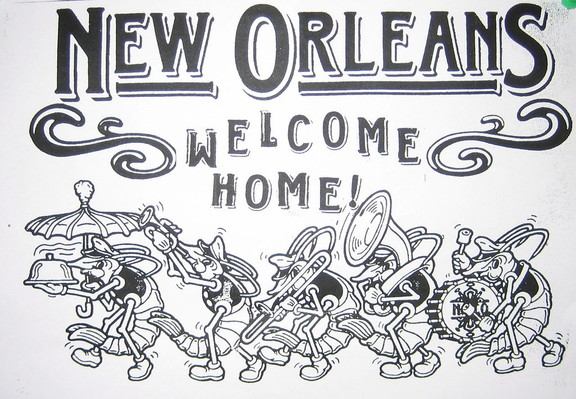 Text: "NEW ORLEANS - WELCOME HOME".

Cartoon of anthropomorphized crwafish having a New Orleans parade. They wear shoes, vests or shirts, and New Orleans brass band musician caps.  The first crawfish holds an umbrella and a covered steaming plate of food. The second plays trumpet, the third trombone, the fourth trombone, the fifth Sousaphone, the last a bass drum. 