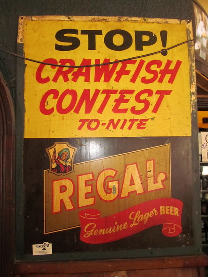 c. mid-20th century wooden sign with paint. 
Top text: "STOP! - CRAWFISH CONTEST - TO-NITE".

Below, logo for long-defunct local "Regal Beer", a man holding a beer bottle. Text: "REGAL - Genuine Lager BEER". 
