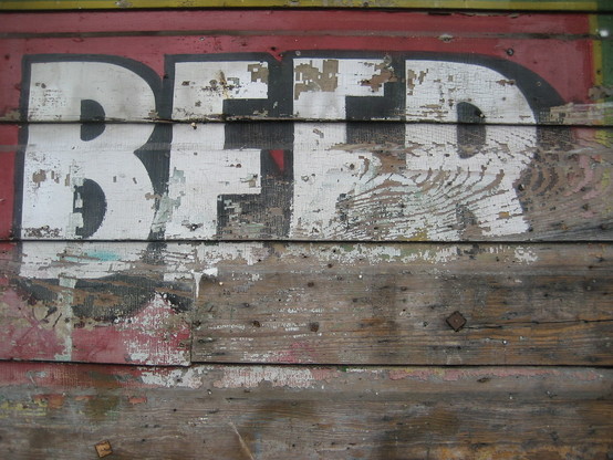 Faded painted sign on wood, reading "BEER". 
