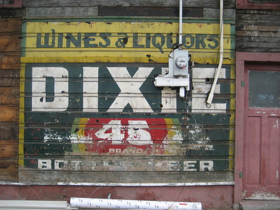 Faded signage painted on weatherboards of old wooden building, 

Text: "WINES & LIQUORS - DIXIE 45 BRAND - BOTTLED BEER"