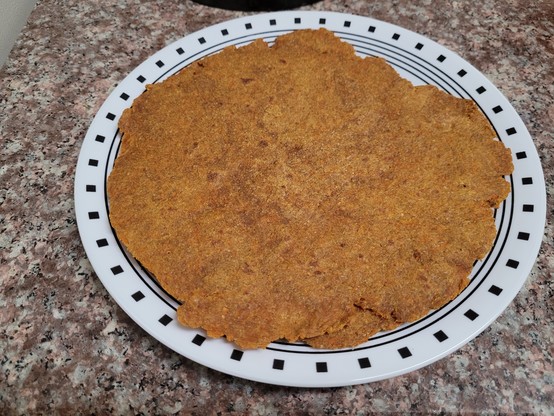 Carrot paratha (orange tortilla-like flatbread) on a white corelle plate with edge decorations.