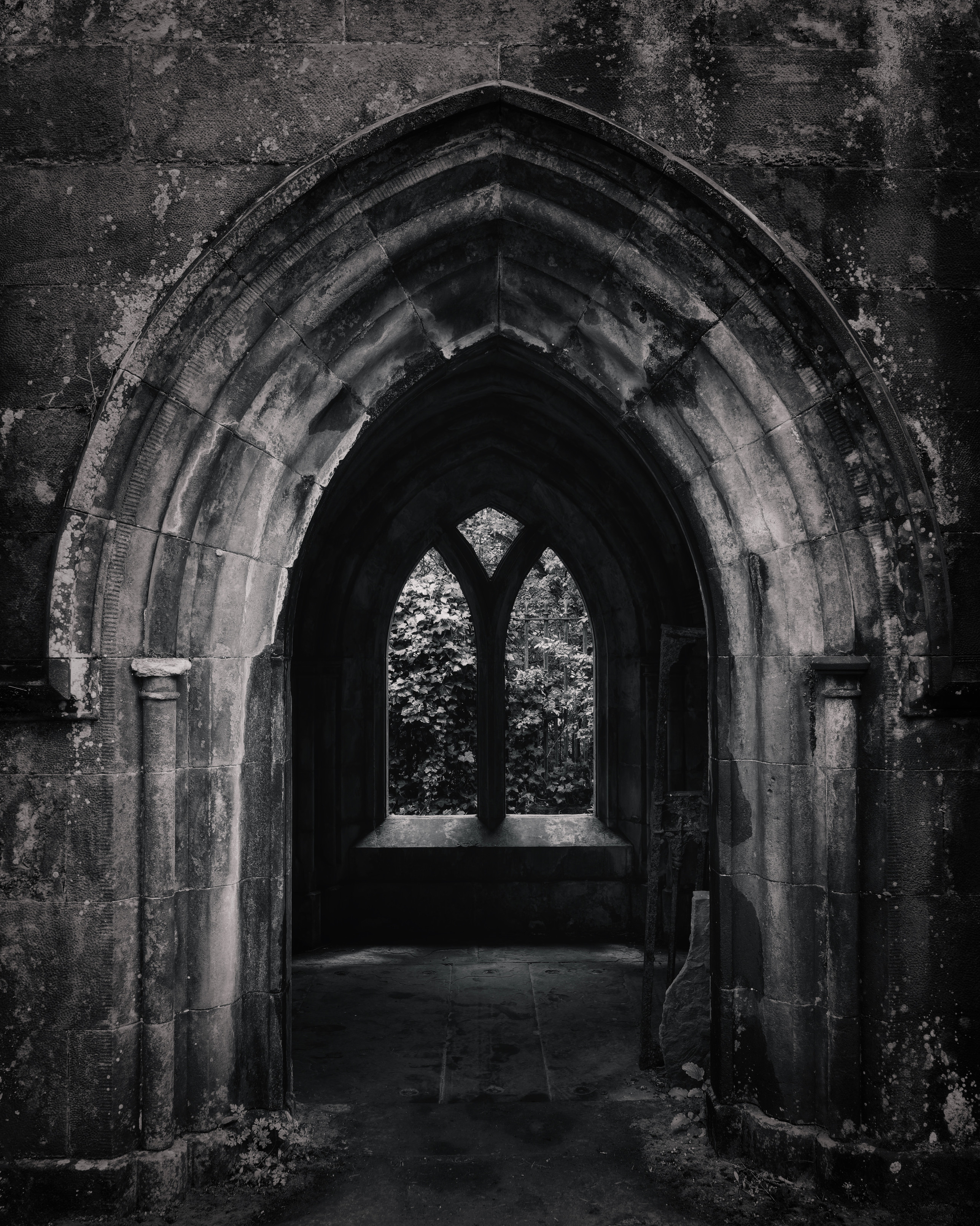 Detailed view of a stone archway in Culross Abbey, looking through to a window onto foliage beyond