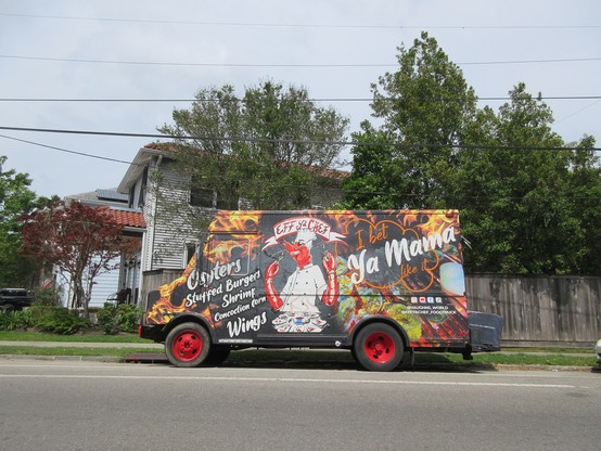 Colorfully painted food truck parked on street, with 2 story house in background.  Central artwork depicts a slightly anthropormophized crawfish wearing a chef's hat and smock.  Text above: "EFF ya CHEF".  Text at left: "Oysters - Stuffed Burgers - Shrimp - Concoction Corn - Wings".  Text at right: "I bet YA MAMA like it". 