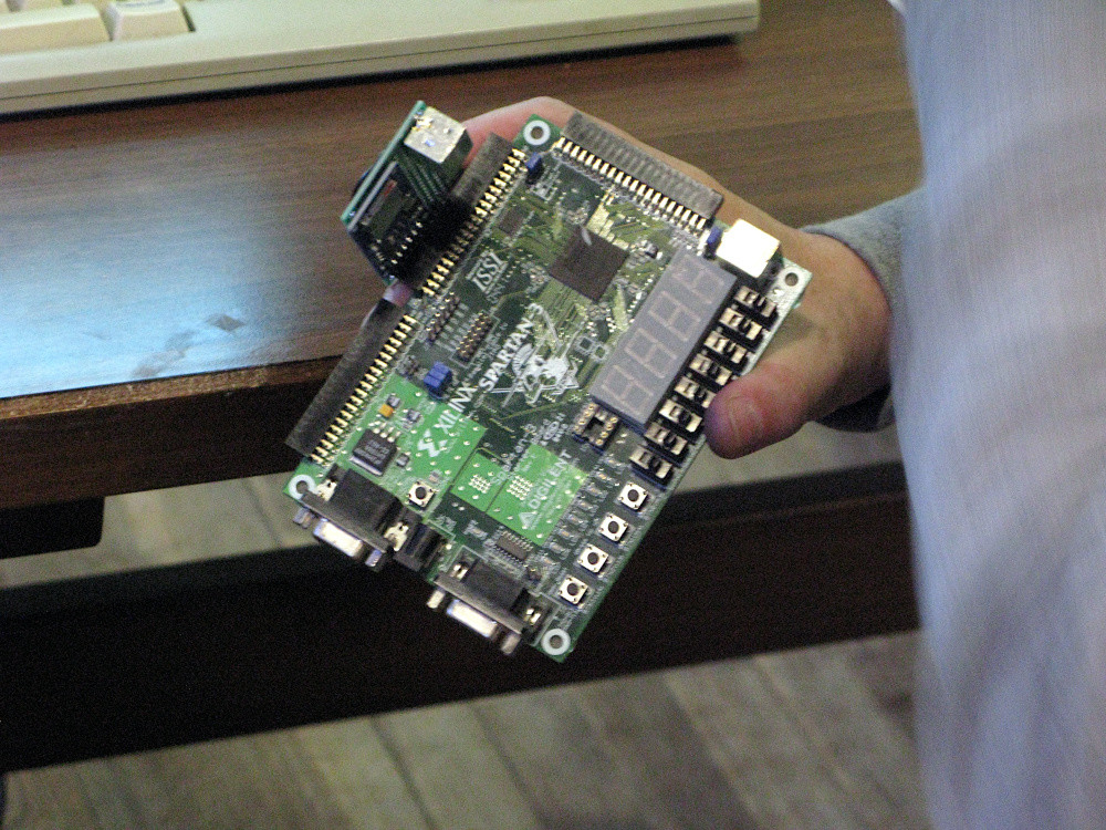 Ein Xilinx Entwicklungsboard Spartan 3 in der Hand von Prof. Engel. An einem Port ist der SD Adapter angesteckt.