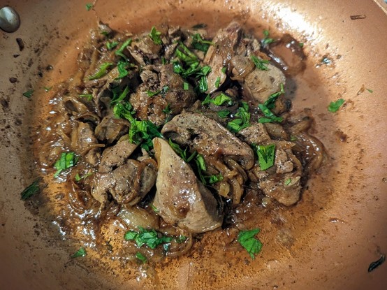 Chicken liver in a pan with browned onions and bits of chopped parsley scattered
