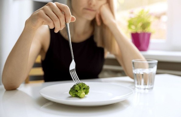 Une personne désabusée plante une fourchette dans un morceau de broccoli