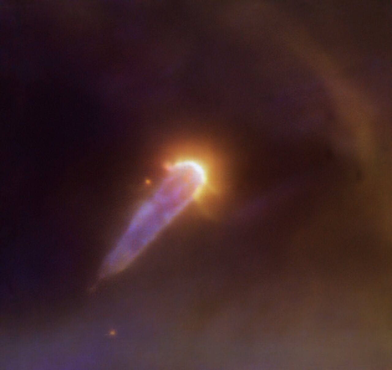 A cosmic cloud shaped like a teardrop. The curved part of the teardrop is bright yellow and points to the upper-right, whereas the "pointy" part is purple and points to the lower-left.