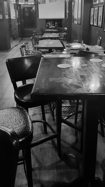 Black and white photo of a bar with empty tables and chairs.